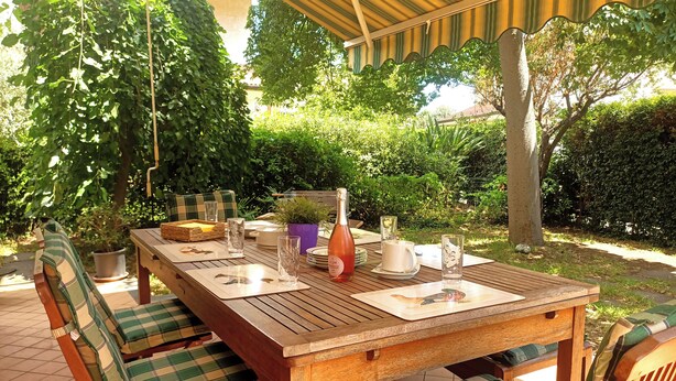 A wooden table set outdoors with chairs, a bottle, glasses, and a pitcher. - Spacious and cozy villa located between the sea and the volcano Etna! (Santa Maria La Stella)