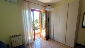 A room with a blue sofa, a radiator, a sliding door leading to an outdoor area, and a hanging light fixture. - Spacious and cozy villa located between the sea and the volcano Etna! (Santa Maria La Stella)