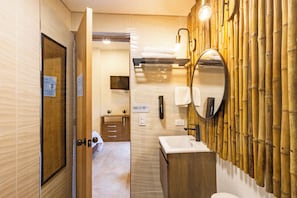 Un baño moderno con tocador de madera, un espejo grande y un diseño de pared de bambú.