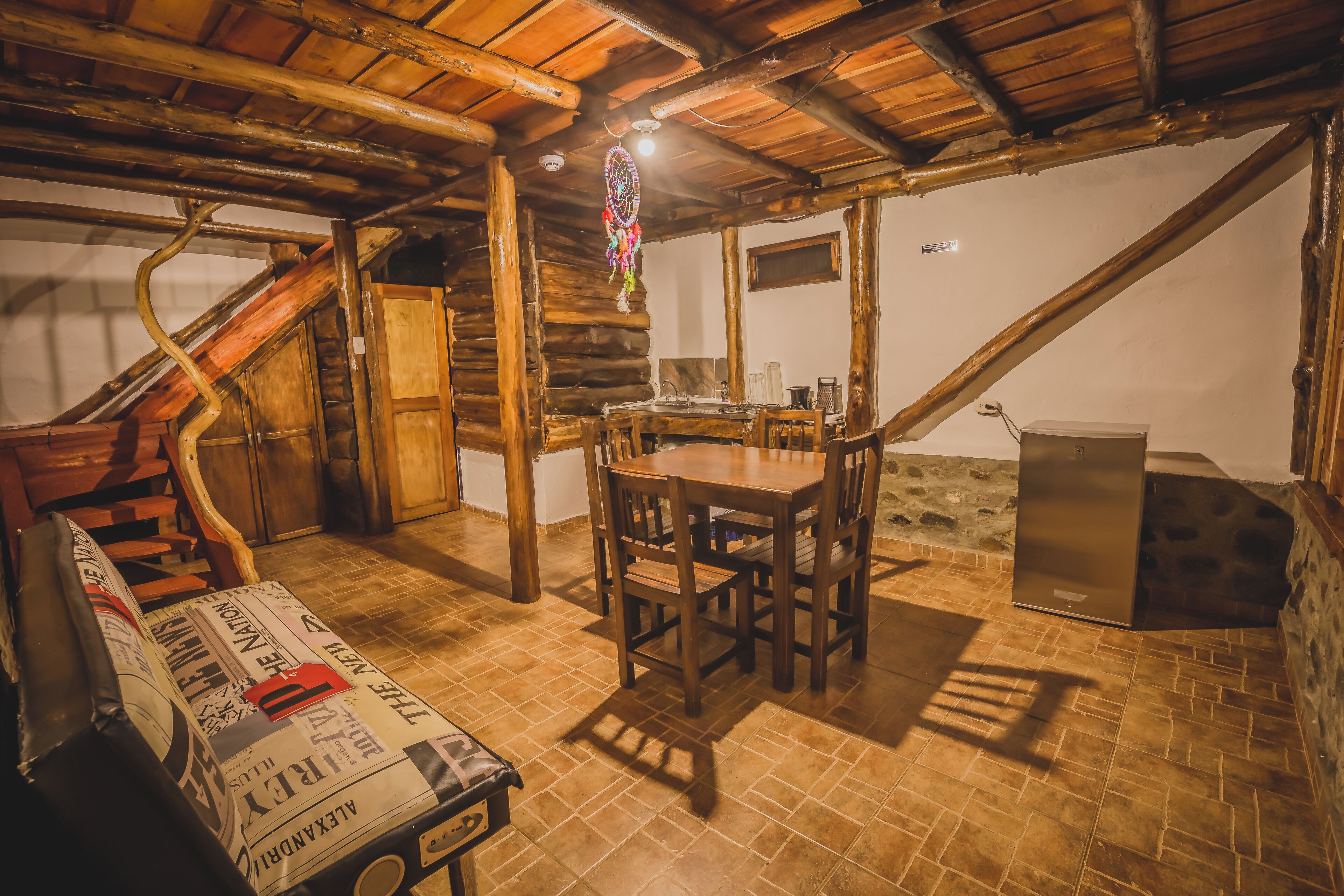 Un coin repas rustique avec une table et des chaises en bois, un mur en pierre et un escalier en bois.