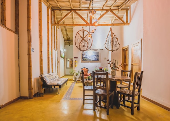 A cozy dining area with a wooden table and chairs, a bench, and hanging decorative items.