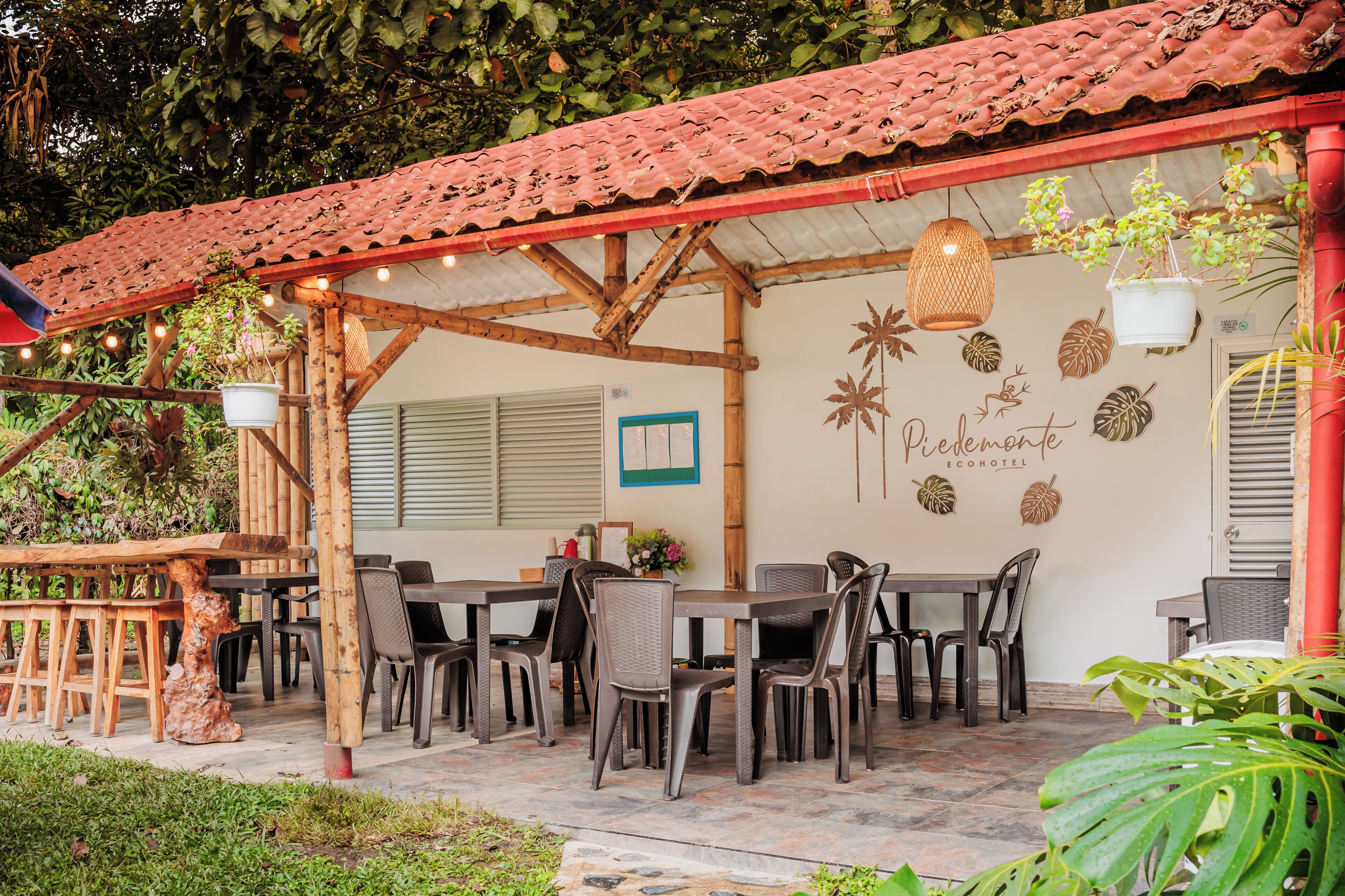 An outdoor seating area with tables and chairs, a red tiled roof, and decorative wall art.