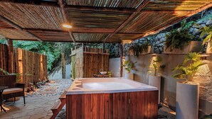 A hot tub in a covered outdoor area with wooden flooring, surrounded by potted plants and a stone wall. - ECOHOTEL PIEDEMONTE (Salento)