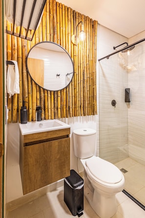 Un baño moderno con pared de bambú, un espejo redondo, un lavabo blanco y un inodoro.