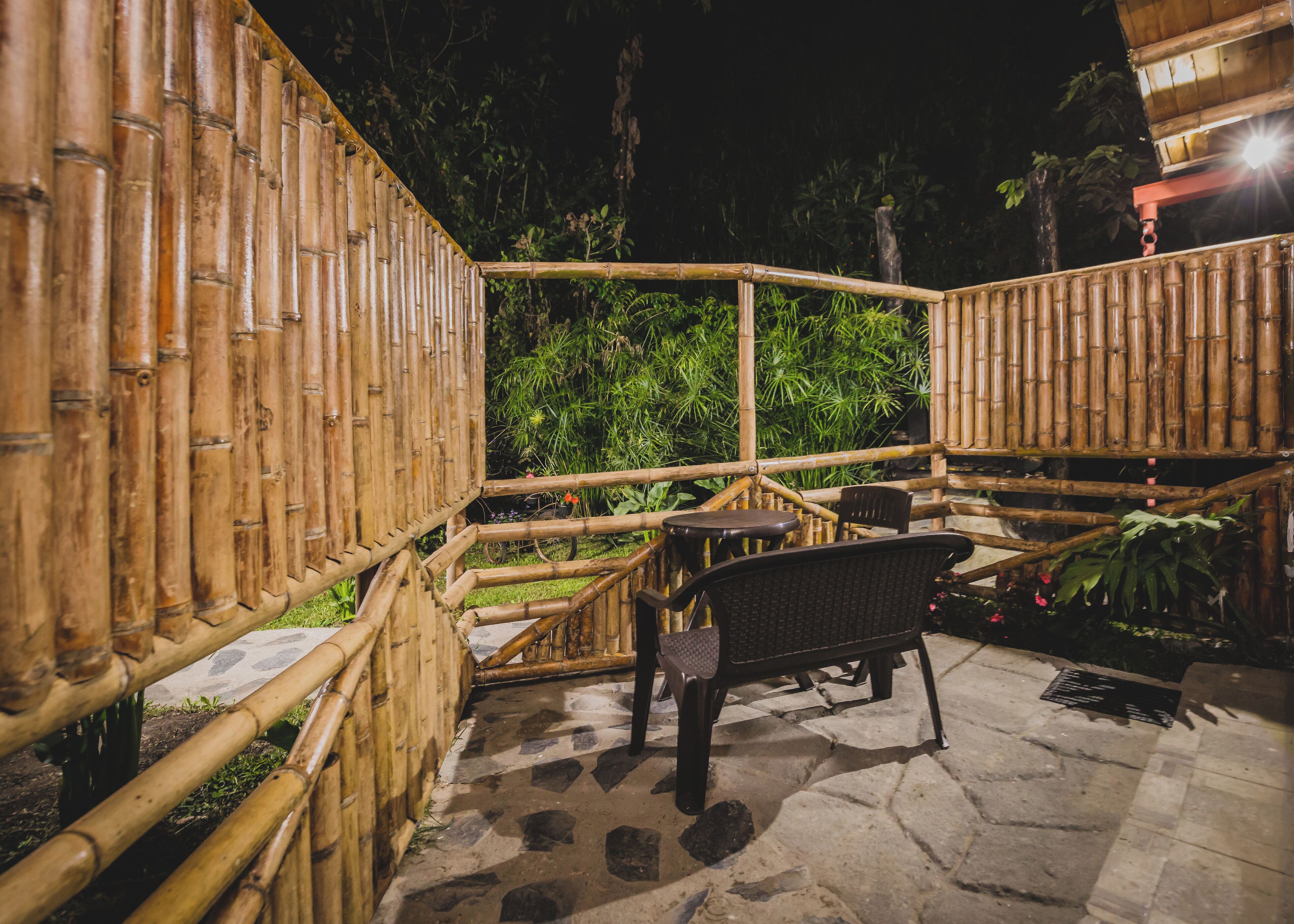 An outdoor bamboo structure with seating and a paved area.