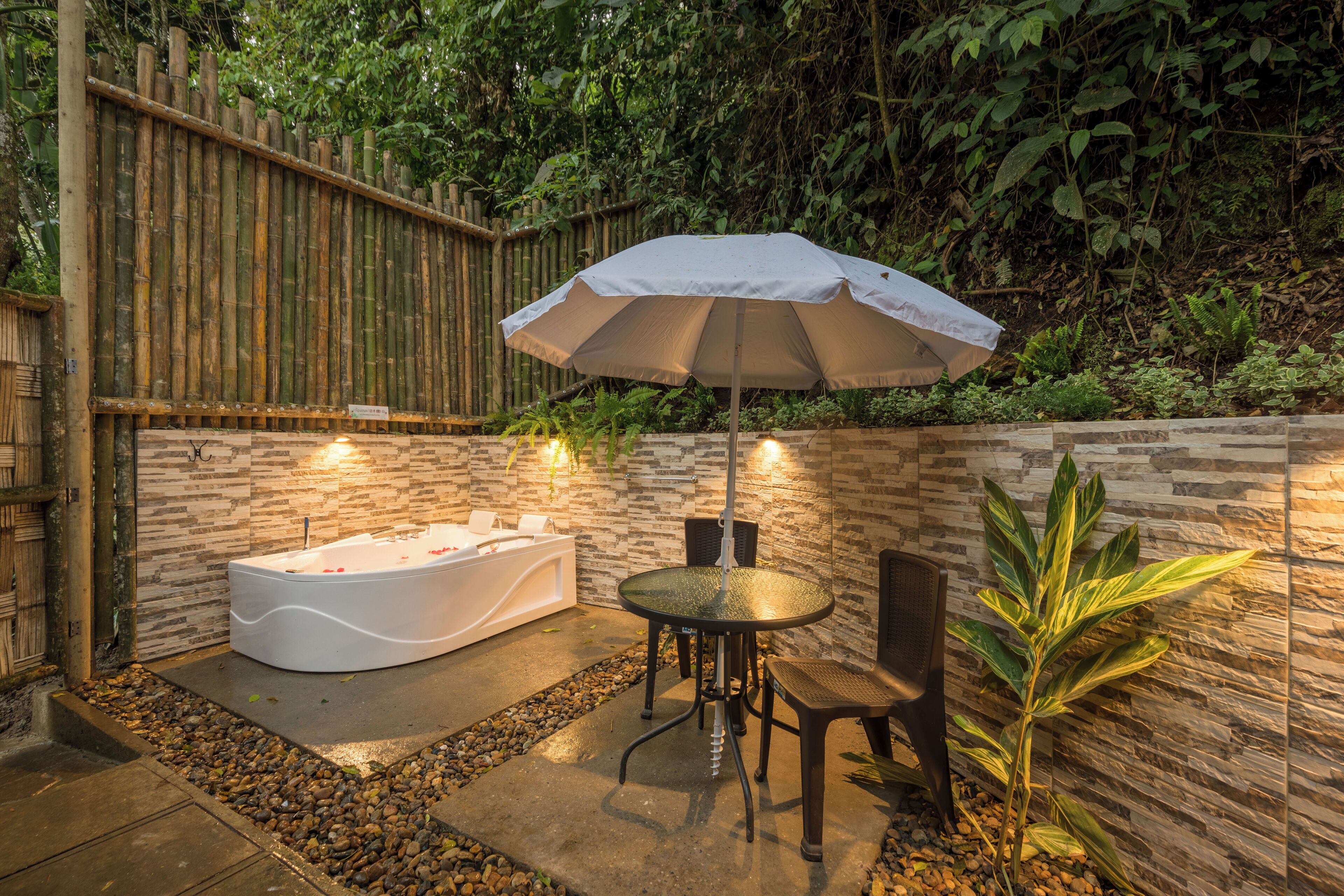 A spa area with a hot tub, a table with chairs, and an umbrella.