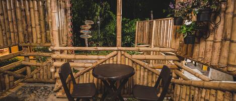 An outdoor seating area with bamboo walls, a stone floor, and a signpost with directional signs.