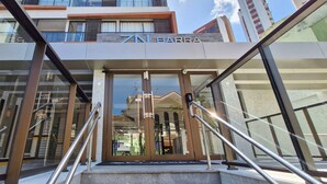 A hotel entrance with glass doors, metal railings, and a clear view of the interior.