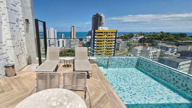 A rooftop pool area with a view of the city and ocean.