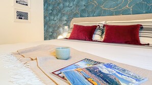 A neatly made bed with a striped pillowcase, a red pillow, and a blue mug on the side. - Feel Naples New, Comfortable, bright and central 2 min from Metro! (Napoli)