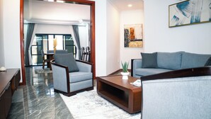 Una sala moderna con un sofá, sillones, una mesa de centro y un comedor con mesa y sillas.