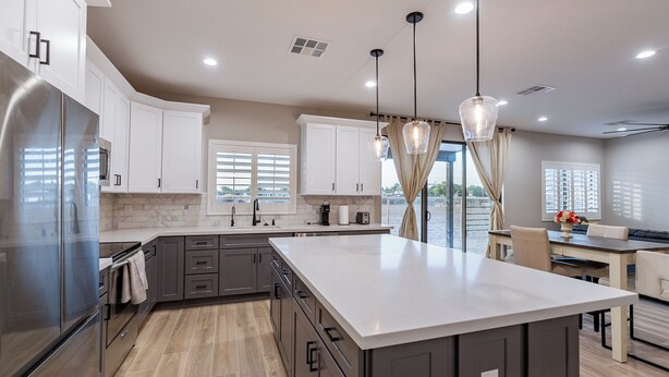 A modern kitchen with a large island, stainless steel appliances, and pendant lighting.