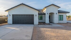 A modern two-story house with a garage, a covered porch, and a small attached structure with a tiled roof.