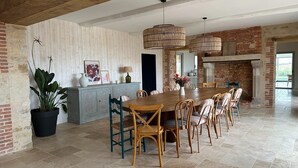A spacious dining area with a long wooden table and chairs, a brick fireplace, and a large potted plant. - Beautiful Villa With Indoor Pool (Sainte-Cecile)
