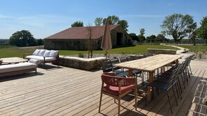 A wooden deck with outdoor furniture, a stone building, and a fenced area. - Beautiful Villa With Indoor Pool (Sainte-Cecile)