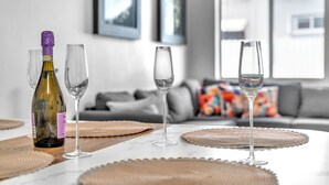 A modern living room with a marble table, wine glasses, and a bottle of wine.