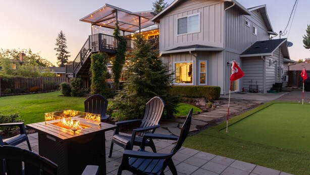 Una casa con terraza, mobiliario exterior y un césped cuidado.