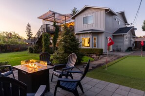 Una casa con terraza, mobiliario exterior y un césped cuidado.