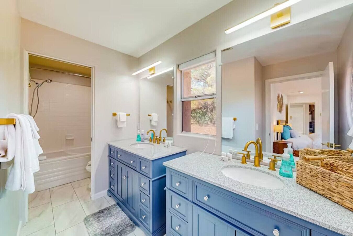 A modern bathroom with two sinks, a large mirror, and a shower area.