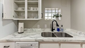 A kitchen with white cabinets, a marble countertop, a double sink, and a coffee maker. - Nest & Nook • 2 Units, 2 Mins from BYU (Provo)