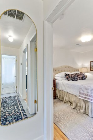 A bedroom with a bed, a nightstand, a lamp, and a large mirror. - Nest & Nook • 2 Units, 2 Mins from BYU (Provo)