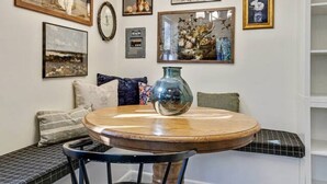 A dining area with a round wooden table, black chairs, a bench with cushions, and a chandelier. - Nest & Nook • 2 Units, 2 Mins from BYU (Provo)