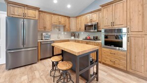 Una cocina moderna con armarios de madera, electrodomésticos de acero inoxidable y una isla central con taburetes.