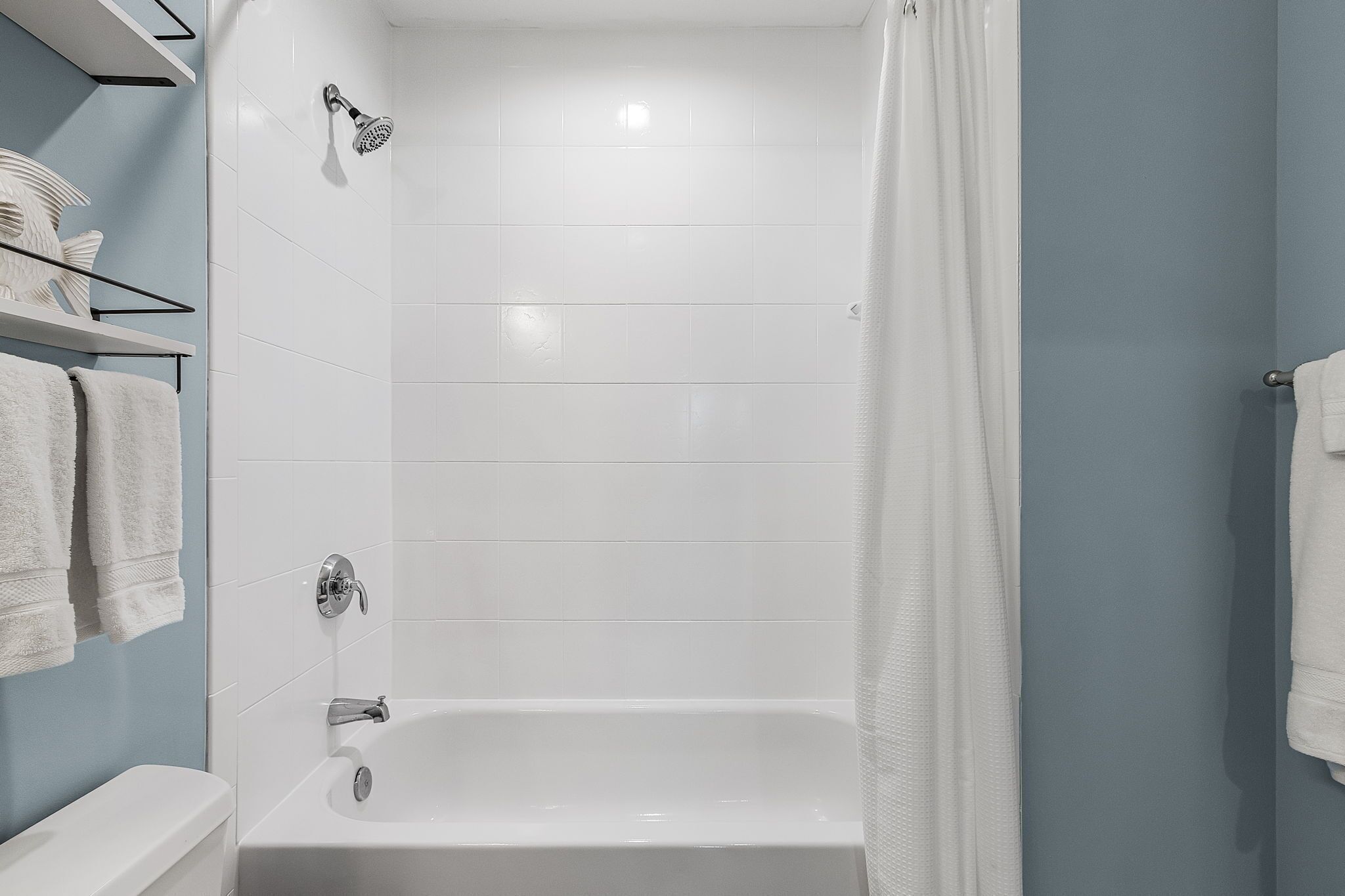 Ein modernes Badezimmer mit Badewanne, Duschkopf und weißen Fliesen.