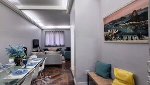 Una sala de estar moderna con comedor, un sofá, un televisor y un cuadro en la pared.