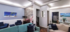 Un vestíbulo de hotel con un sofá color turquesa, un sofá color beige y una escalera que sube a otro nivel.