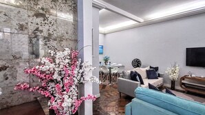 Una sala de estar moderna con un pilar de mármol, un sofá, una mesa de centro y un televisor montado en la pared.