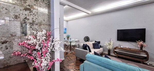 A modern living room with a marble column, a sofa, a coffee table, and a TV mounted on the wall.