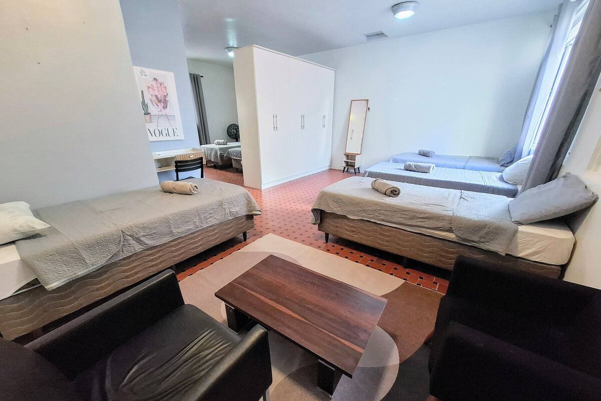 A hotel room with two single beds, a desk, a chair, and a small table.