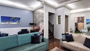 Sala de estar con dos sofás, una mesa de centro y un televisor. Una escalera conduce a otra habitación.