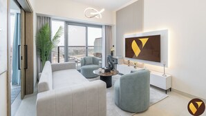 Un salon moderne avec un canapé, des fauteuils, une table basse et un téléviseur fixé au mur.