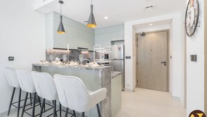 Une cuisine moderne dotée d’un îlot central, de tabourets de bar, de luminaires suspendus et d’une porte en bois.