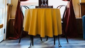 A room with a table set for two, draped with red curtains, and a window with a view. - Hotel San Ramon (Bisbee)