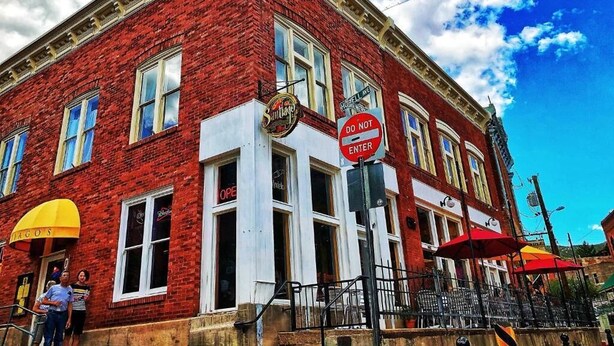 A red brick building with a 'DO NOT ENTER' sign, a 'DAGOS' sign, and a 'HUSSELL AVE' sign. - Hotel San Ramon (Bisbee)