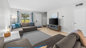 Un salon moderne avec un canapé, un téléviseur et une petite table sur laquelle se trouve une lampe.