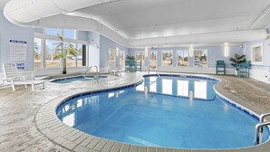 Una piscina de diseño curvo, rodeada de sillas de descanso y plantas en macetas.
