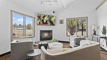 A living room with a fireplace, large windows, and modern furniture.