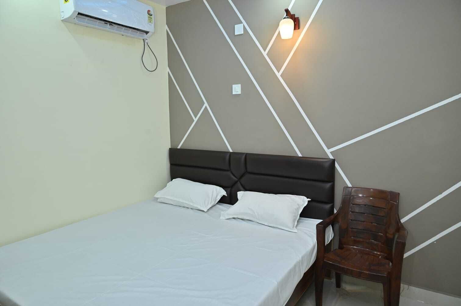 Una cama individual con cabecera, aire acondicionado de pared y una lámpara de pared.