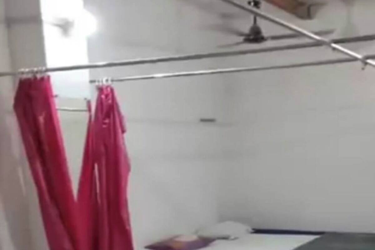 Ein Zimmer mit mehreren Betten, jedes mit einer Matratze und einem Kopfkissen. Ein Bett hat einen Vorhang.