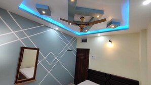 Een slaapkamer met een bed, een plafondventilator, inbouwverlichting, een spiegel en een geometrisch wandontwerp.