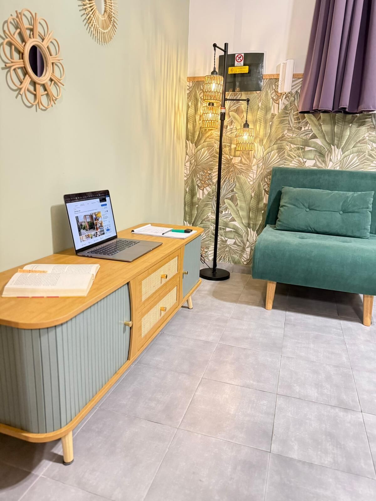 Ein Zimmer mit Schreibtisch, Laptop und einem grünen Sofa.