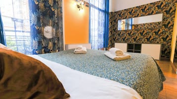 Ein Hotelzimmer mit einem großen Bett, einem Nachttisch mit Lampe, einem Spiegel und einer Wand mit Muster.
