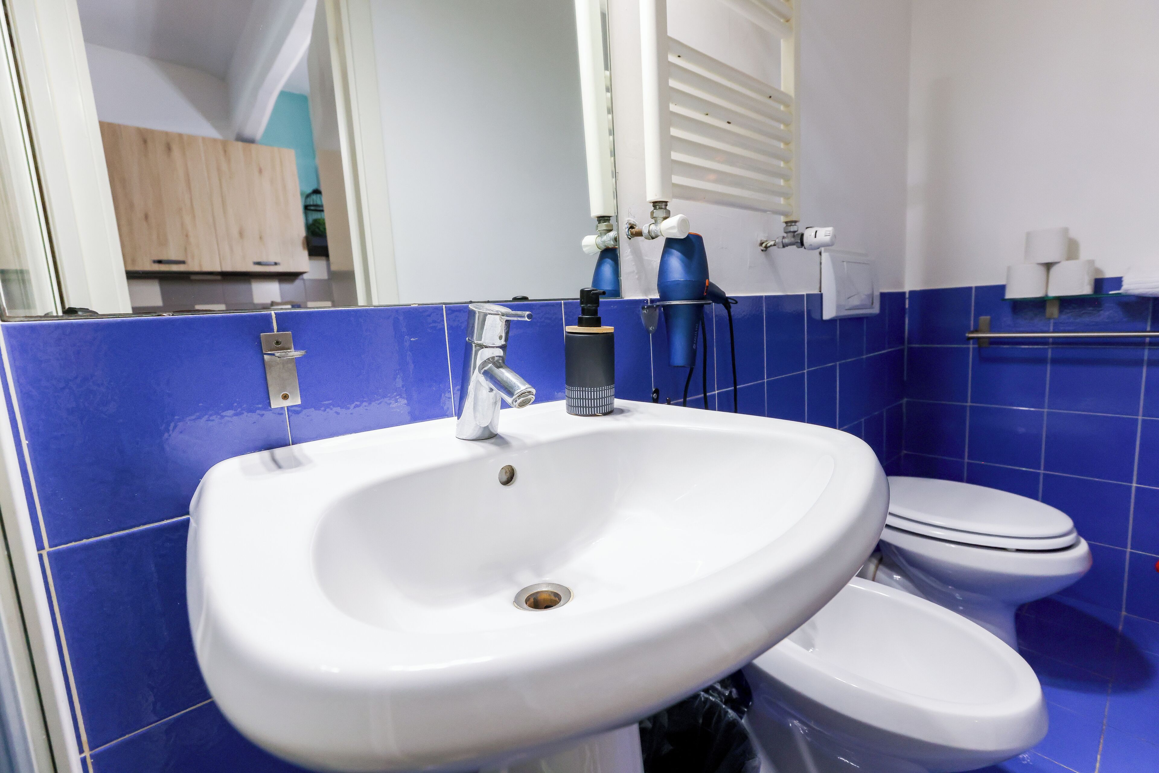 Ein Badezimmer mit einem weißen Waschbecken, einer Toilette und blauen Fliesen.