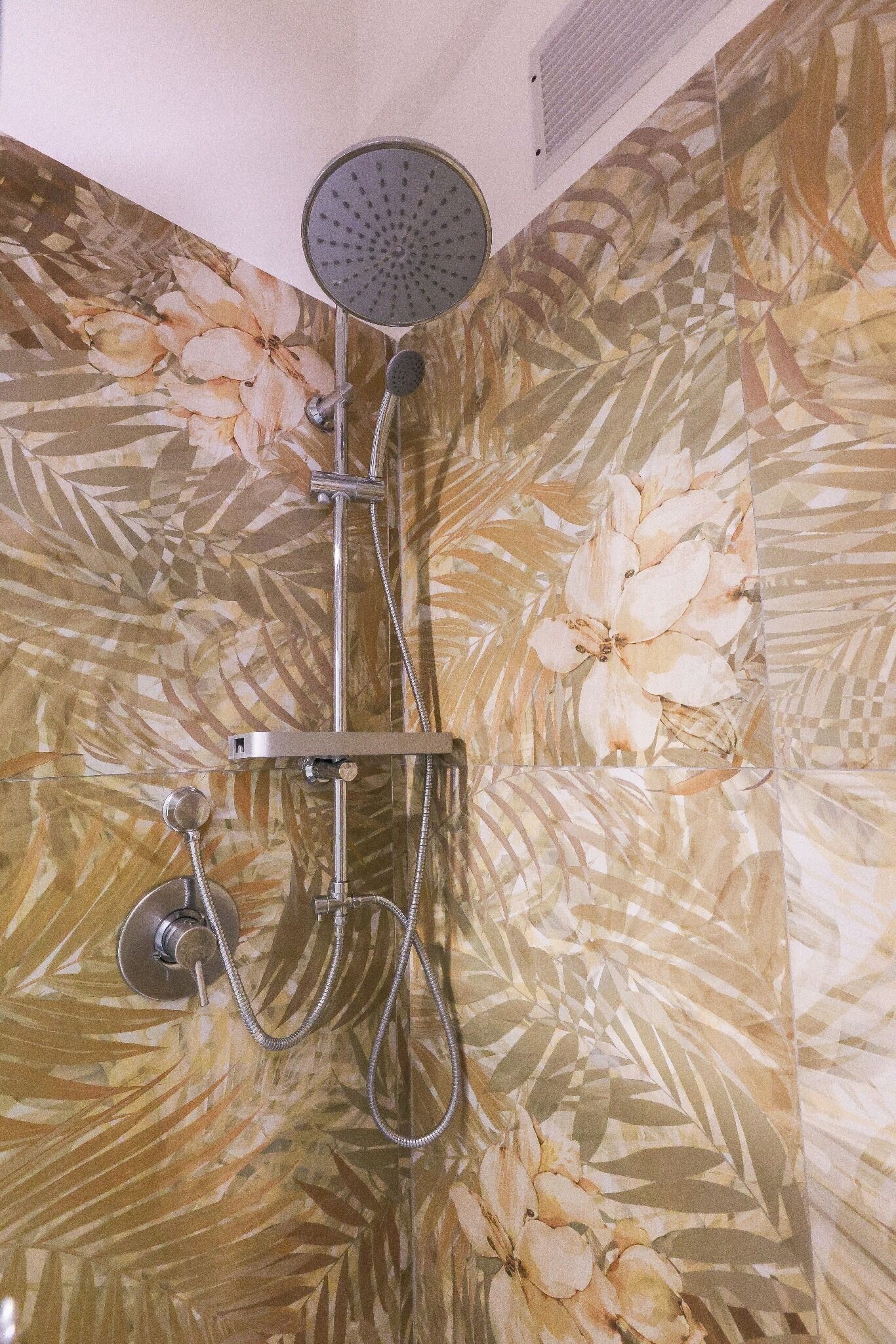 Een douche met een bloemmotief op de wand.