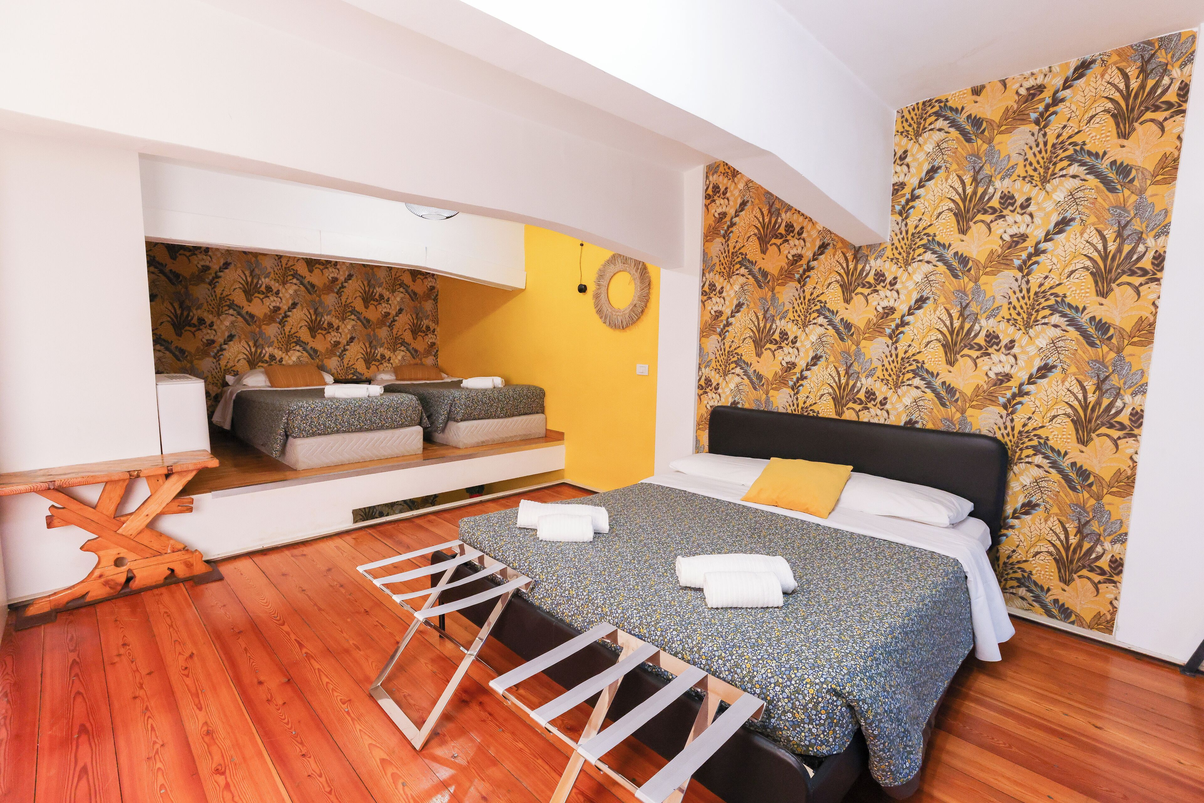 Een slaapkamer met een bed, een zithoekje en een wand met bloemenbehang.