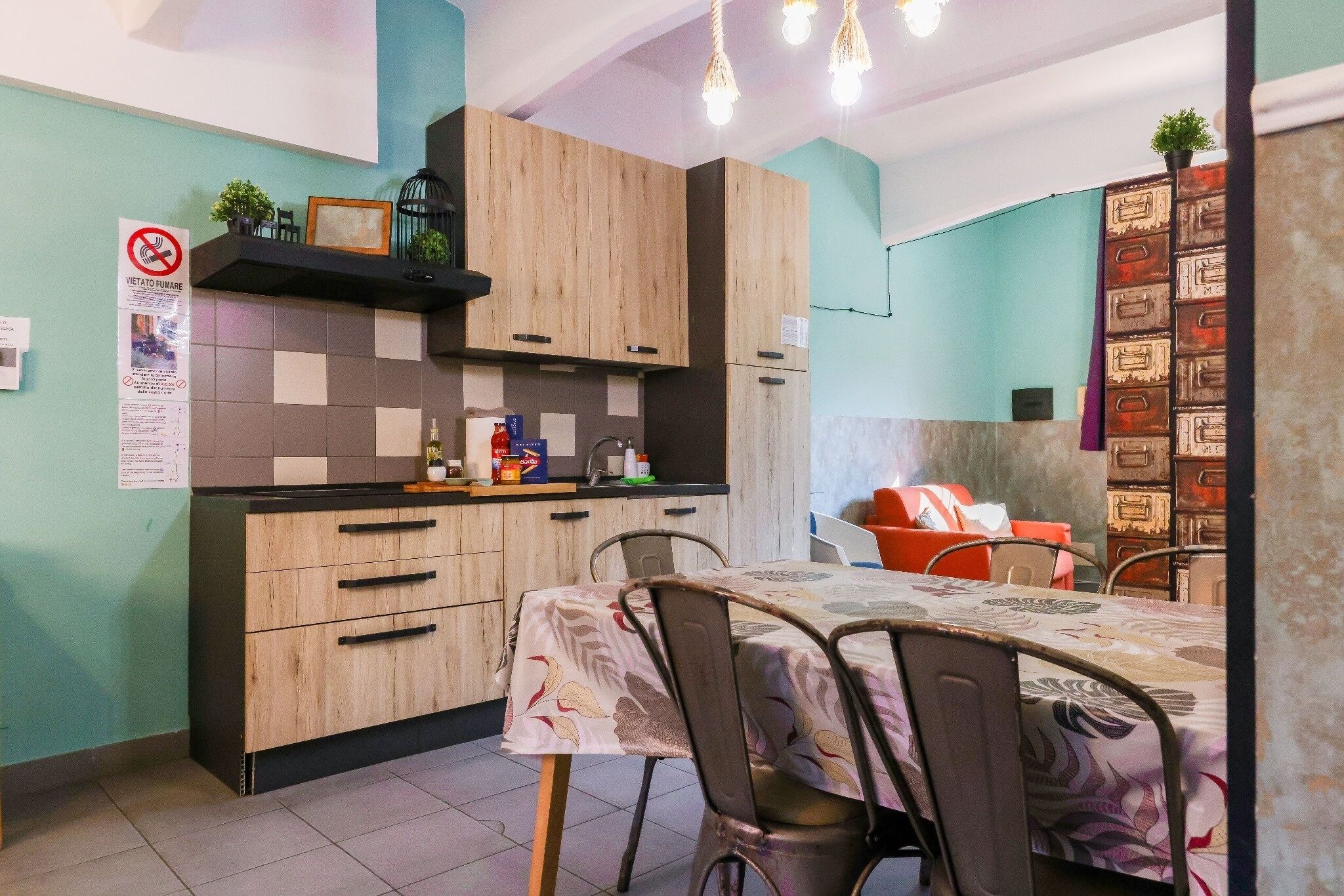 Una cocina con armarios de madera, una mesa de comedor con sillas y un refrigerador pequeño.